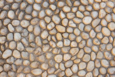 Beton yolda beyaz çakıl taşı. Üst görünüm taşı arka planı. Deniz kenarındaki çakıl taşı fotoğraf dokusu. Taş kaldırım yüzeyi. Doğal dış dekorasyon malzemesi yuvarlanmış kaldırımlar