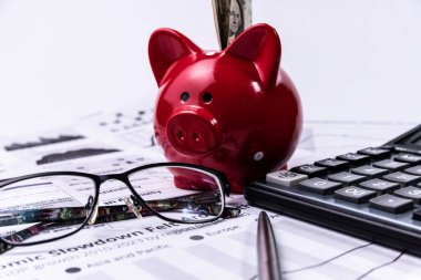 İş belgelerinde para ve hesap makinesi olan bir kumbara.