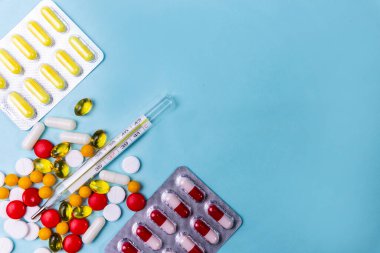 Mavi arka planda haplar ve termometre.