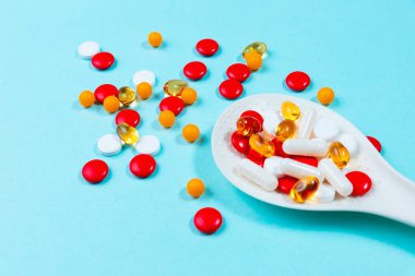 Mavi arka plandaki kaşıkta haplar. Yakın plan.