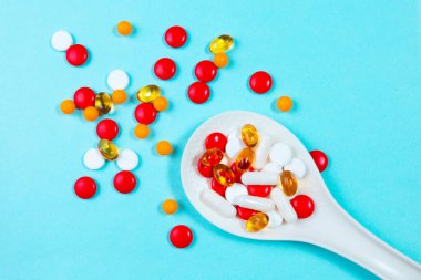 Mavi arka plandaki kaşıkta haplar. Yakın plan.