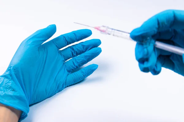 Medical syringe in hand with blue glove isolated on white background. Injection