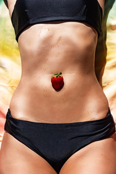 Strawberry on skin near navel and panties line, healthy food concept, sensual