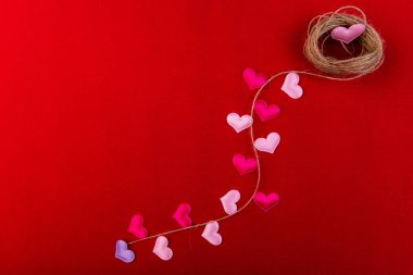 Kırmızı arka planda küçük kalpler ve keten iplikler. Sevgililer Günü.