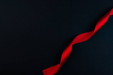 A spiral of red satin ribbon, on a black background.