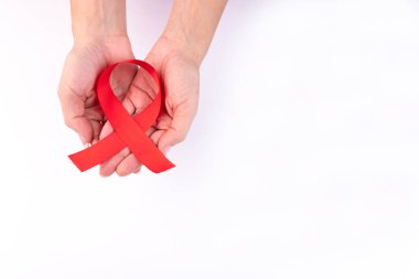 Beyaz arka planda AIDS farkındalığının sembolü olarak kadınların ellerinde kırmızı kurdele..