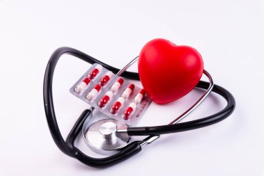 Sesli kalp, fonendoskop ve beyaz arka planda haplar. Kalp hastalığı olan hastalara destek kavramı.