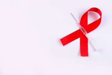 Beyaz arka planda şırınga ve kırmızı kurdele. Dünya AIDS Günü.