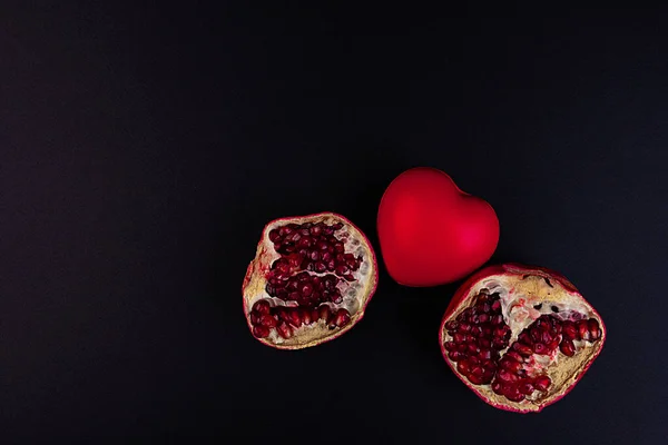 Broken pomegranate and heart on a dark background.