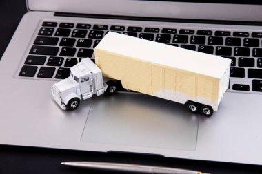 Siyah arka planda oyuncak kamyon ve dizüstü bilgisayar