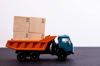 Oyuncak kamyon arkasında kargo taşıyan kutular taşıyor.