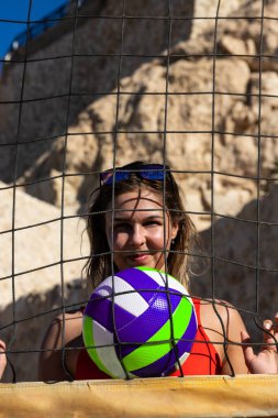 Sharm El Sheikh, Mısır - 12.25.2019: Voleybol sahasında kırmızı mayo giymiş genç bir kız. Plaj voleybolu.