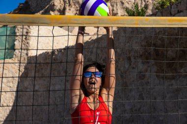 Sharm El Sheikh, Mısır - 12.25.2019: Voleybol sahasında kırmızı mayo giymiş genç bir kız. Plaj voleybolu.