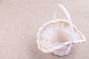 Beyaz hasır sepet keten bir masa örtüsünün üzerinde duruyor.