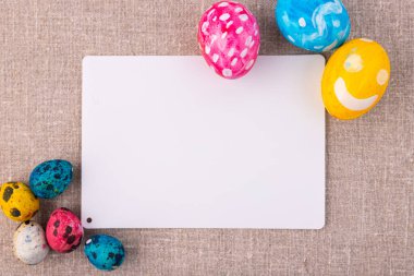 Paskalya kompozisyonu, keten bir yüzeyde yumurtalar. Bir yazı için beyaz kart.