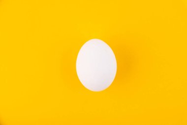 Ortadaki sarı arka planda beyaz yumurta. Tasarım, görsel sanat, minimalizm