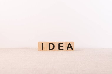 Hafif arka planda tahta küplere yazılmış IDEA yazıları. Yaratıcı fikirler ve yenilikler kavramı.