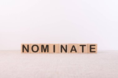 Beyaz arkaplandaki yapı taşlarından yapılan NOminate sözcüğü