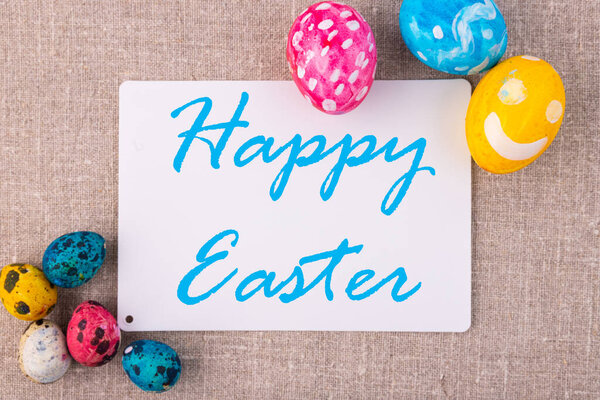 Easter composition with eggs on a linen surface. White card for an inscription.