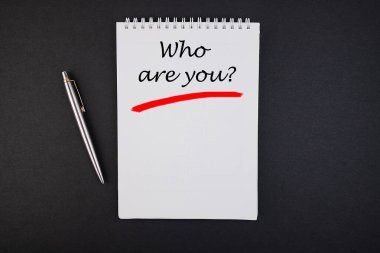 Üzerinde yazı olan defter. Siyah bir masanın üzerinde kim var?.