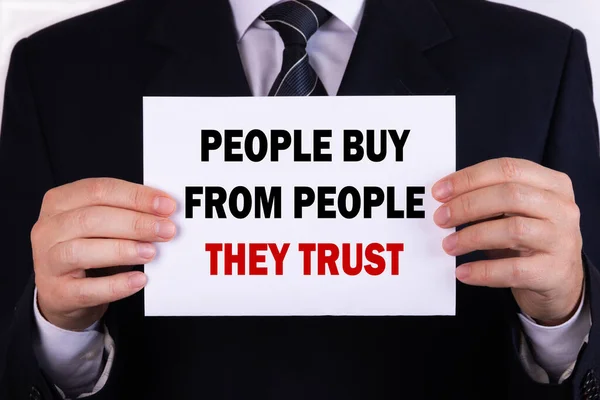 Businessman holding a card with text People Buy From People They Trust