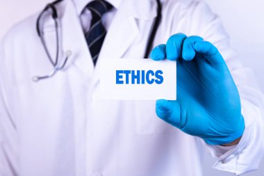 Doktor elinde metin etik tıbbi konsepti olan bir kart tutuyor.