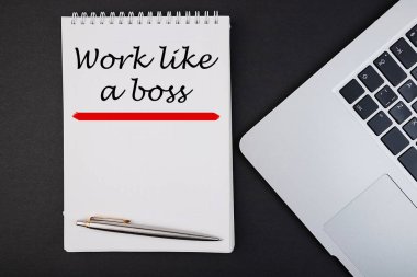 Karanlık bir arka planda dizüstü bilgisayar ve kalemle gezinen bir patron gibi çalış.