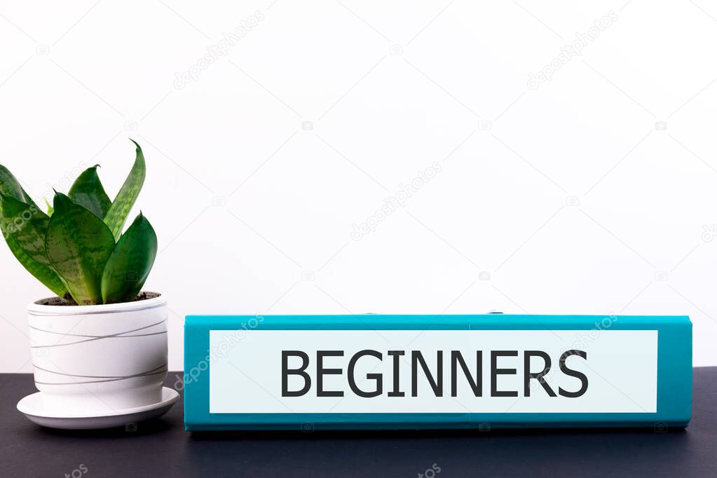 Word Beginners is written on a folder on a dark table with a flower and a light background.