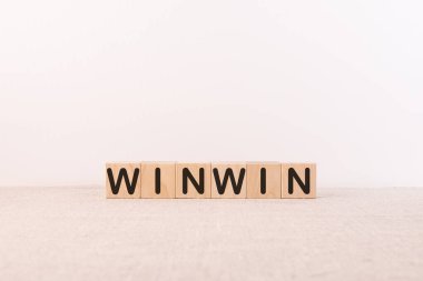 WINWIN kelime kavramı tahta küpler üzerine yazılmış bir ışık tablosu ve ışık arkaplanı üzerinde yatıyor