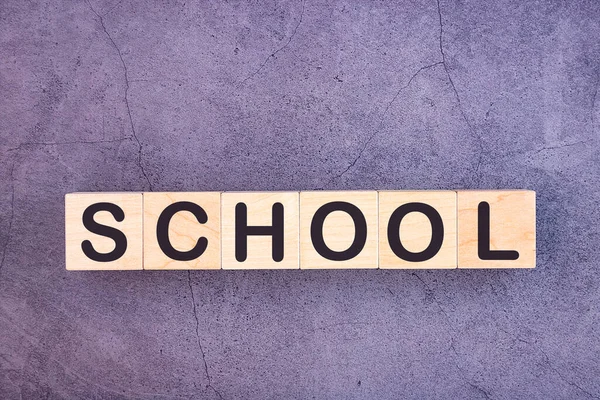 Ahşap yapı taşlarından yapılmış okul kelimesi.