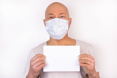 Tıbbi maskeli hasta bir adam beyaz bir arka planda duruyor. Virüs enfeksiyonuna karşı koruma kavramı.