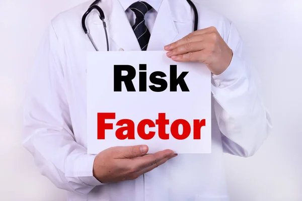 Doctor holding a card with Risk factor medical concept.