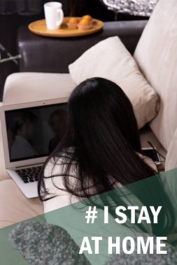 Evde karantina sırasında dizüstü bilgisayarı ve akıllı telefonu olan mutlu kadın: Coronavirus 'u önlemek için sosyal medya kampanyasında kalıyorum