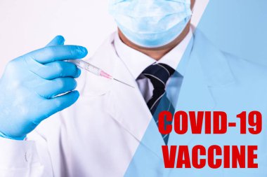 Doktor elinde COVID-19 aşısı olan bir şırınga tutuyor. COVID-19 'un önlenmesi, aşılanması ve tedavisinde kullanılır..