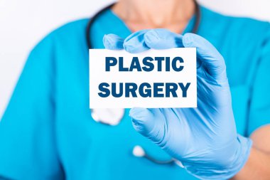 Doktorun elinde Plastiksel SÜRGERY yazılı bir kart var. Tıbbi konsept.