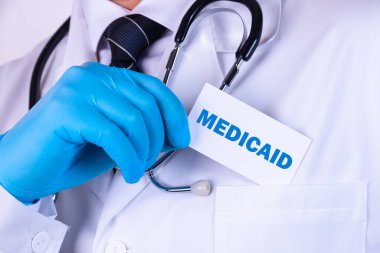 Doktor, adamın biri cebine içinde MEDICAID yazan bir kart koymuş. Tıbbi konsept.
