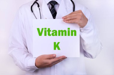 Doktorların elindeki bir karta K vitamini yazılmış.