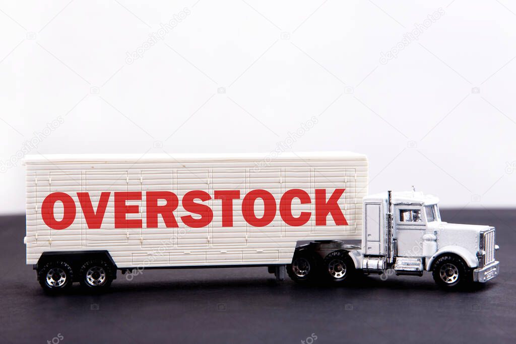 Overstock word concept written on board a lorry trailer on a dark table and light background