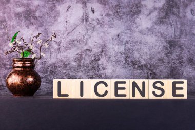 Kelime LICENSE gri arka planda ahşap yapı taşları ile yapılmış.
