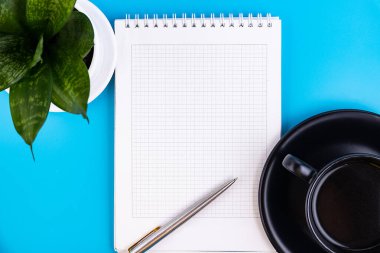 Boş beyaz bir defter aç, içinde kalem, çiçek ve mavi bir masanın üzerinde bir fincan kahve olsun. İş konsepti