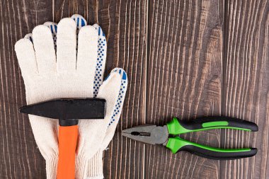 İşçiler, inşaat eldivenleri ve ahşap arka plandaki aletler. Evi temizle. Onarım yapmak için. Bir saatliğine kocacığım..