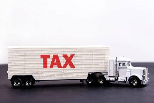 TAX word concept written on board a lorry trailer on a dark table and light background