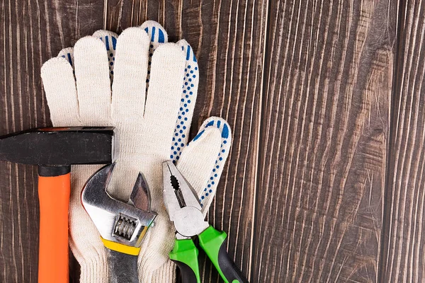 Workers, construction gloves and tool on a wooden background. Clean the house. To make repairs. Husband for an hour.