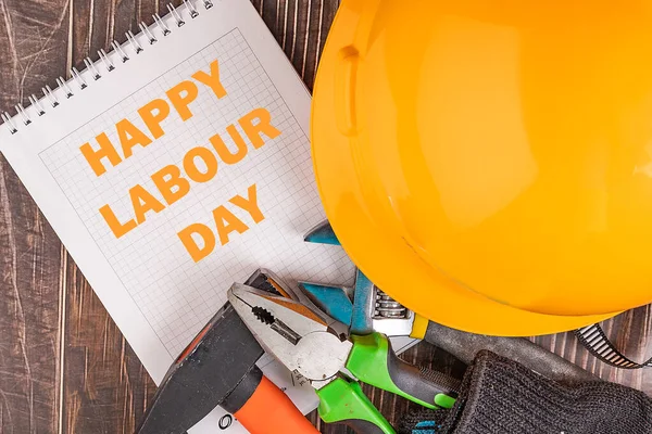 Workers\' day background concept - many handy tools, notebook with happy workers\' day text , wooden background, top view