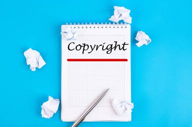 Telif hakkı metni, yazı, yazı, mavi bir masada kalemle duran bir deftere yazılmış cümleler. İş konsepti.