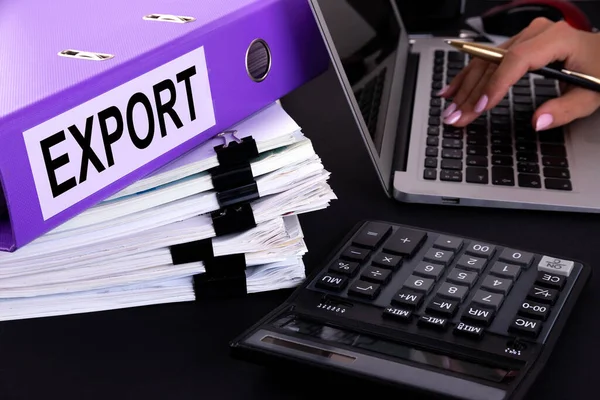 Metin, kelime EXPORT bir klasöre yazılmıştır bir ofis masasında dizüstü bilgisayar ve hesap makinesi ile birlikte. İş konsepti.