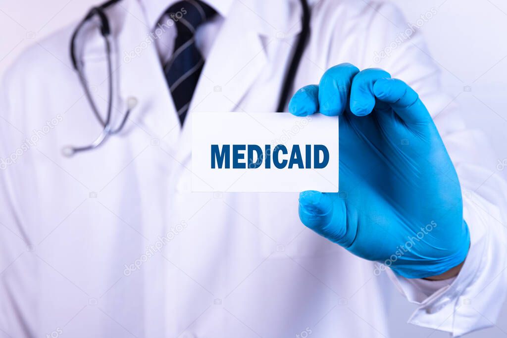 Doctor holding a card with text MEDICAID medical concept.