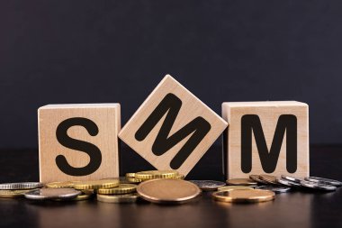 Sözcük SMM küpleri ve tahta yüzeyde istiflenmiş paralar