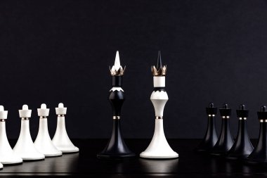 Koyu bir arka planda satranç tahtasındaki beyaz ve siyah satranç taşları. İş konsepti. Oyun, strateji, bilgelik, kararlılık.
