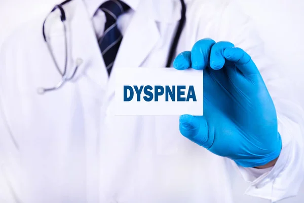 A doctor in medical clothing holds a card with the text DYSPNEA. Medical concept.